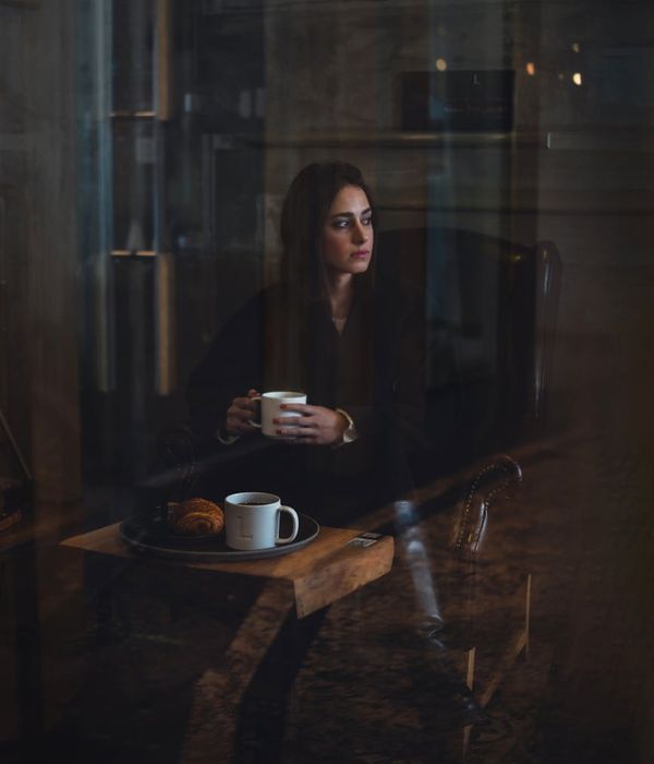 Woman in a calm yoga pose in a dark room with warm ambient light.